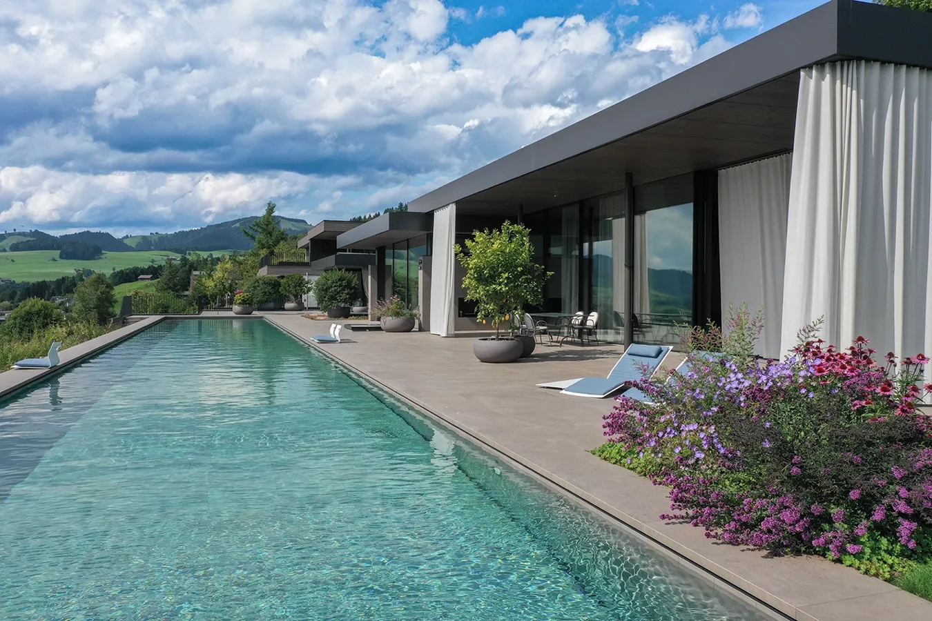 Piscina a sfioro con rivestimento in gres porcellanato Moov Moka Ceramiche Keope, villa privata a Uetliburg con vista sulle Alpi.
