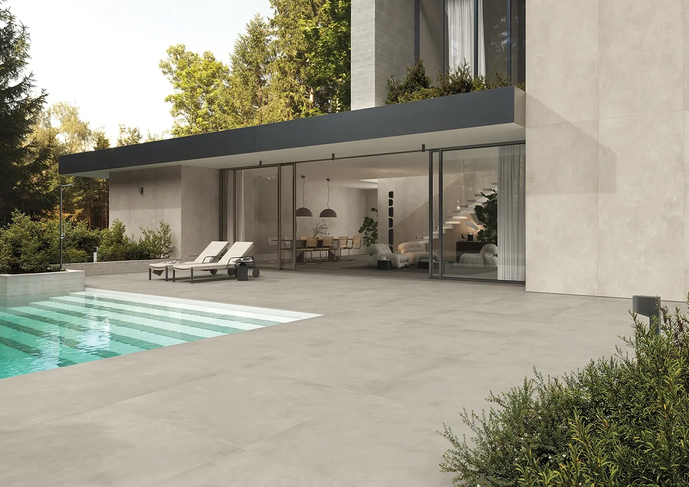 Dalles en grès cérame grand format effet béton au bord d'une piscine avec chaises longues