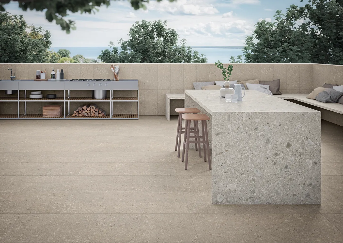 Dalles en grès cérame effet pierre calcaire gris chaud sur une terrasse avec cuisine extérieure et vue sur la mer