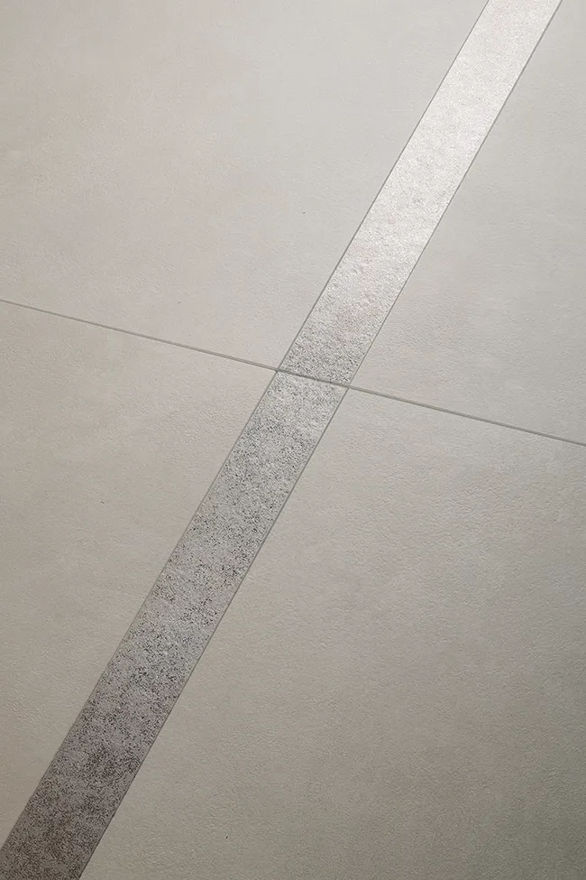 Baldosas aspecto cemento ultramate con detalle de franja decorativa mostrando el acabado superficial antirreflejo.