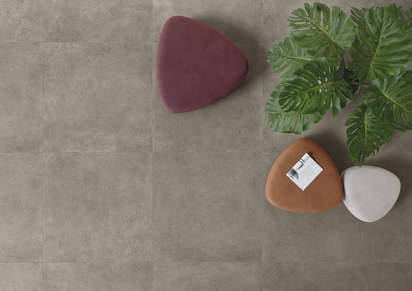Baldosas efecto cemento mate de gran formato con muebles modernos y plantas vista desde arriba.