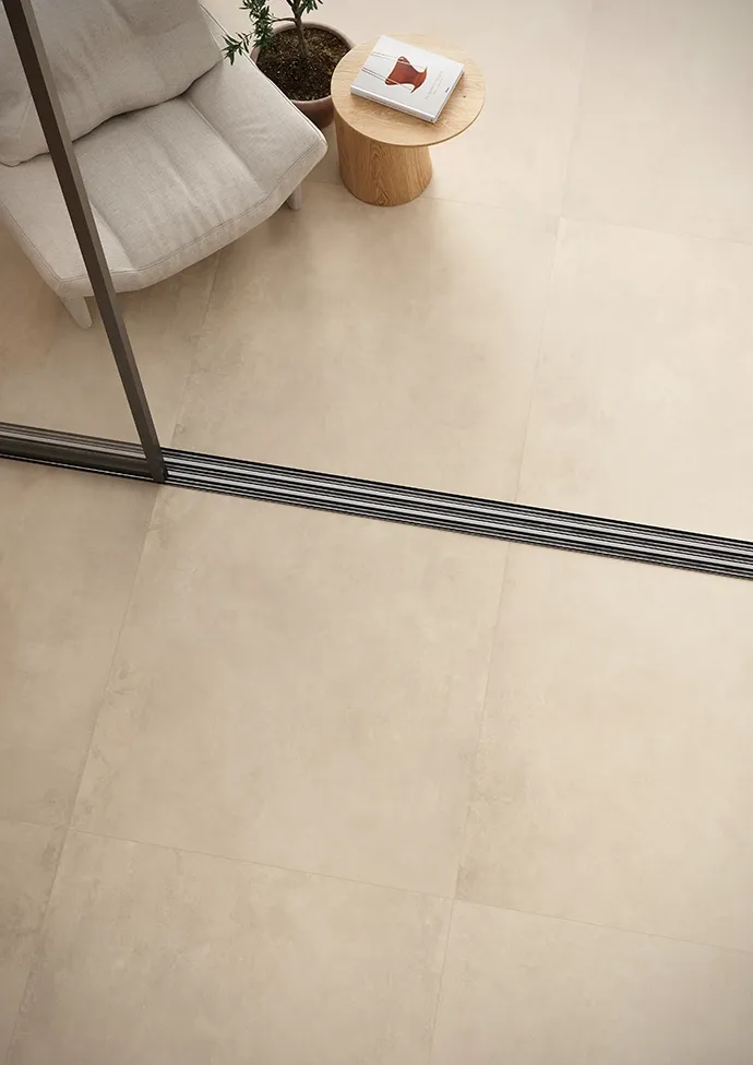 Piastrelle beige in gres porcellanato con fughe grigio scuro e bordo con scarico lineare nero.