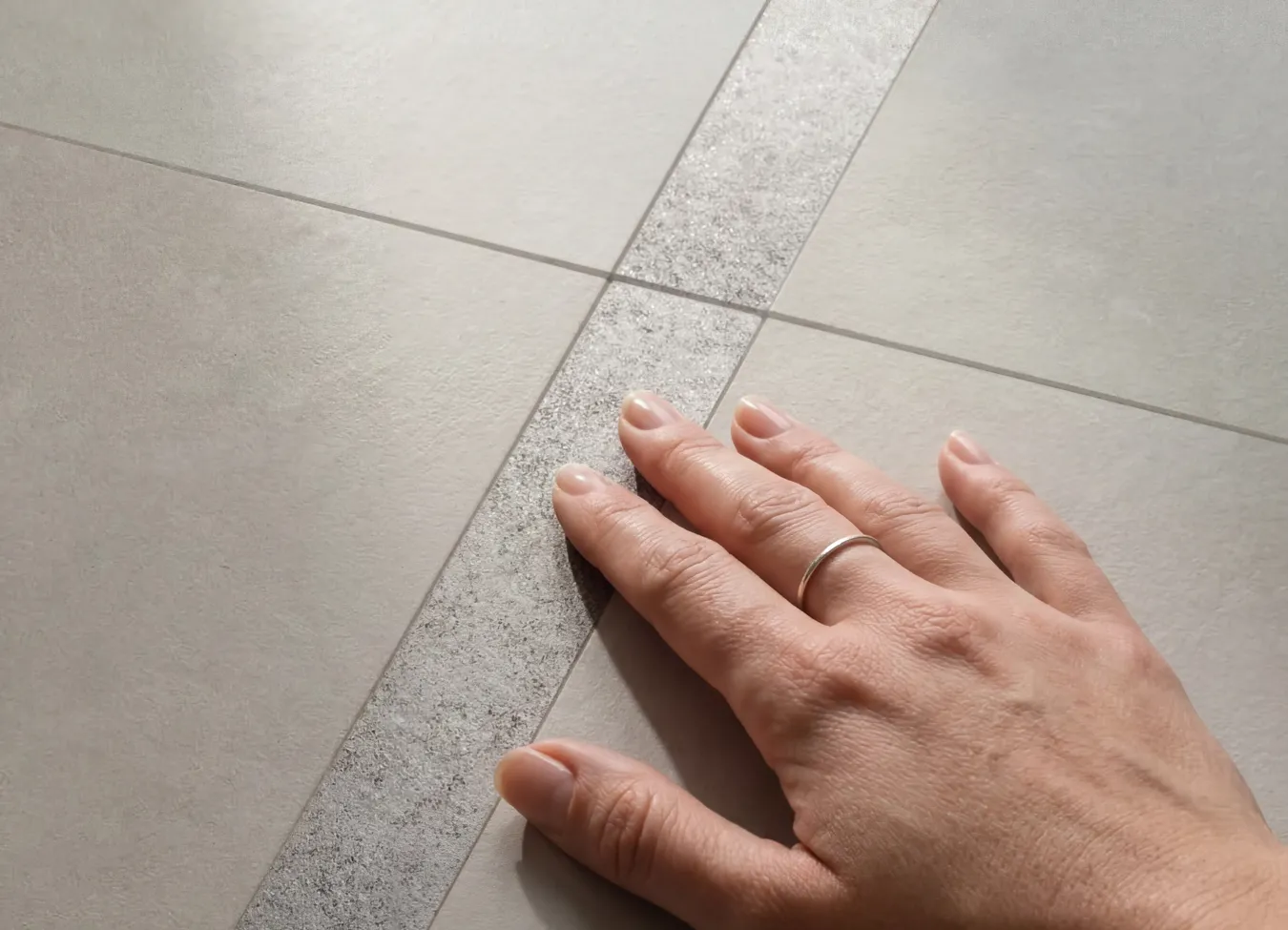 Рука касается поверхности керамогранита под камень.