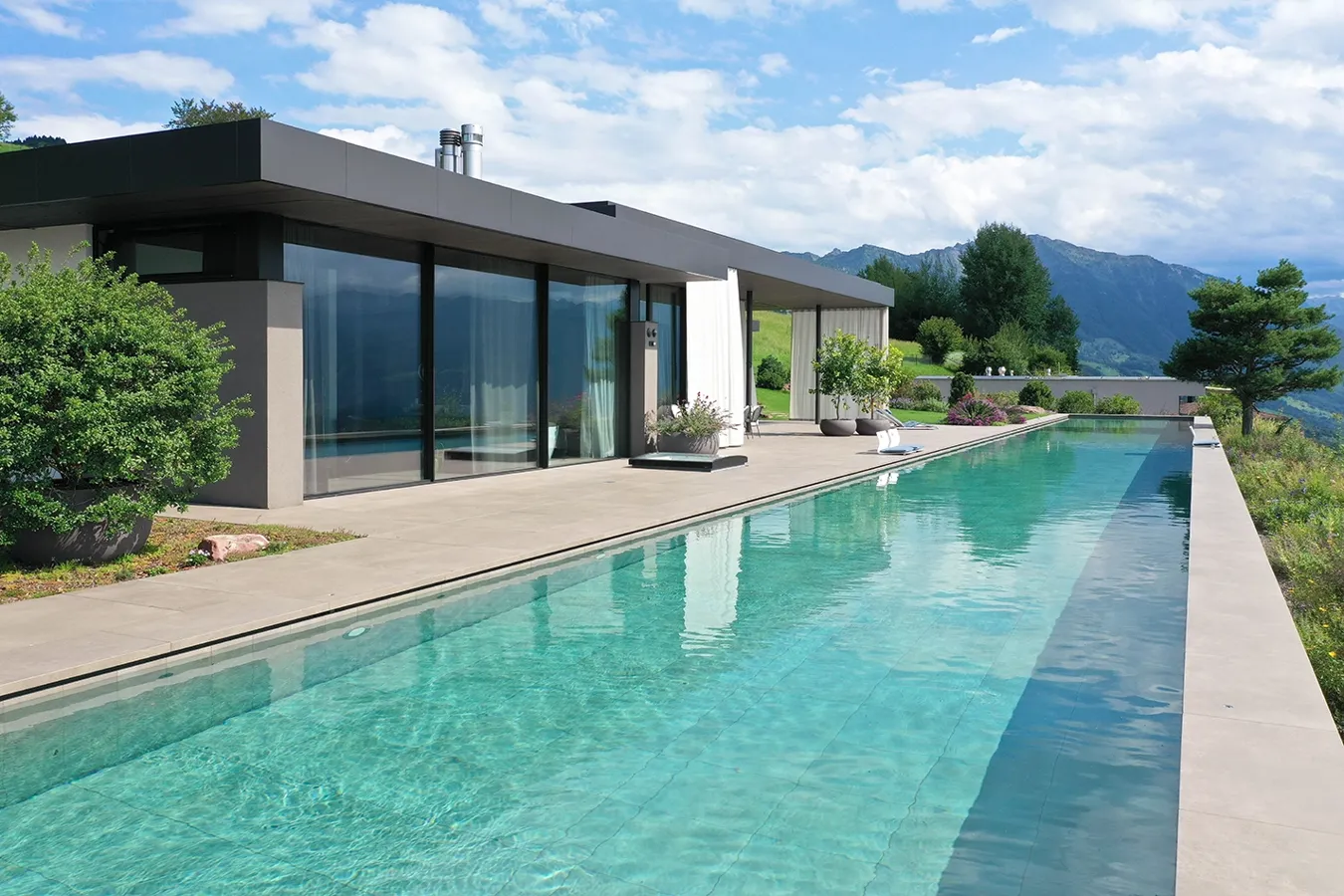 Piscina a sfioro con rivestimento in gres porcellanato Moov Moka Ceramiche Keope, villa privata a Uetliburg con vista sulle Alpi.