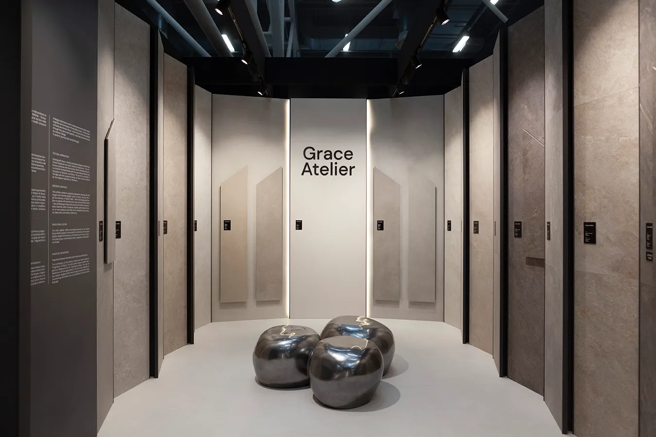 Ceramiche Keope exhibition display at Cersaie featuring Grace Atelier limestone-effect porcelain tile panels and metallic seating.