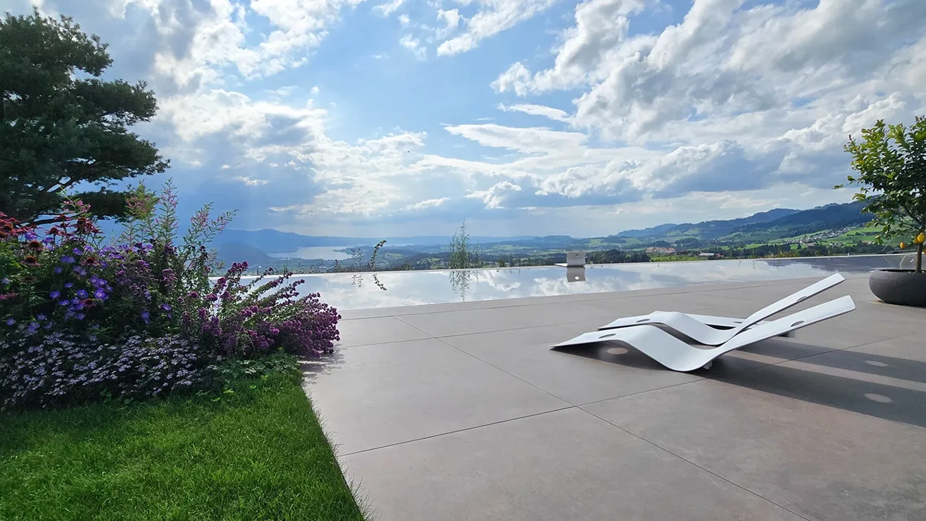 Villa privata a Uetliburg con ampie superfici outdoor rivestite in Moov Moka di Ceramiche Keope, piscina e giardino integrati nel paesaggio.