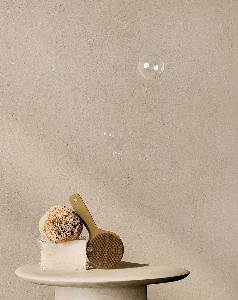 Gros plan de la surface en grès cérame effet pierre calcaire Keope Grace Beige avec accessoires de bain naturels