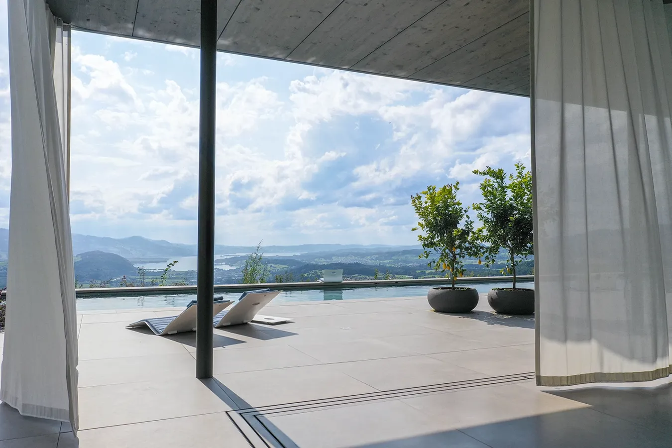 Terrazza moderna in gres porcellanato Moov Moka di Ceramiche Keope, zona relax esterna con vista panoramica alpina.