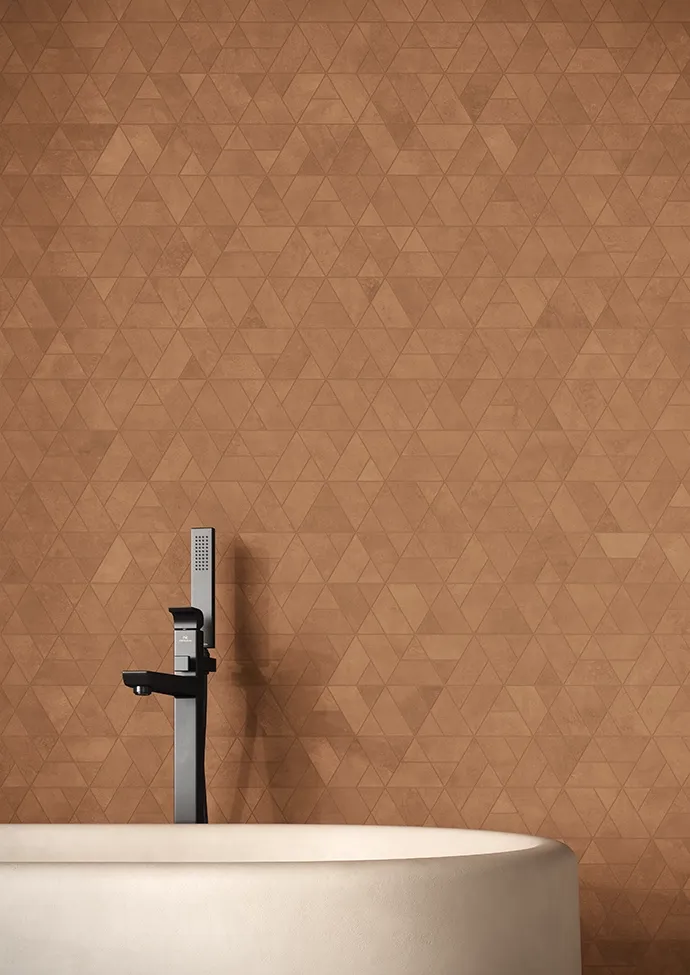Détail de douche avec carrelage mural en grès cérame effet microciment Keope Moov Up Coffee à motif géométrique en chevron dans des tons bruns chauds