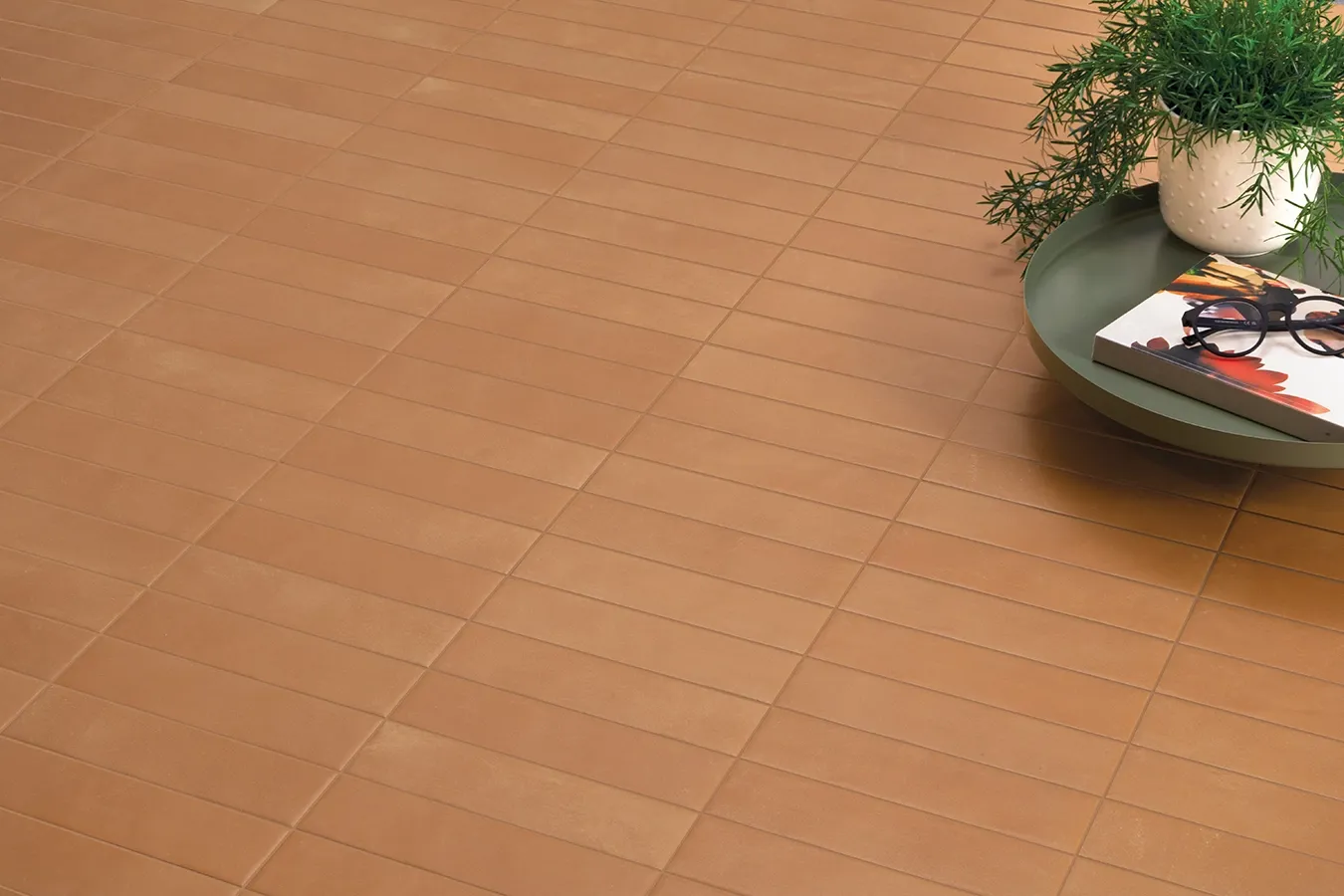 Terracotta look porcelain tiles for indoor floors with natural warm tones and side table.